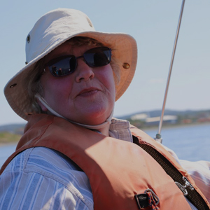 mature woman in Tilley hat and lifejacket aboard a sailboat smiling